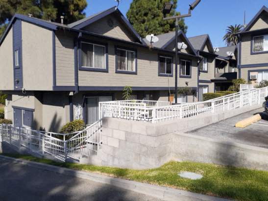 A row of houses with a white fence in front.